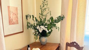 Une table en bois sur laquelle se trouvent un vase de fleurs, un chapeau et des livres.