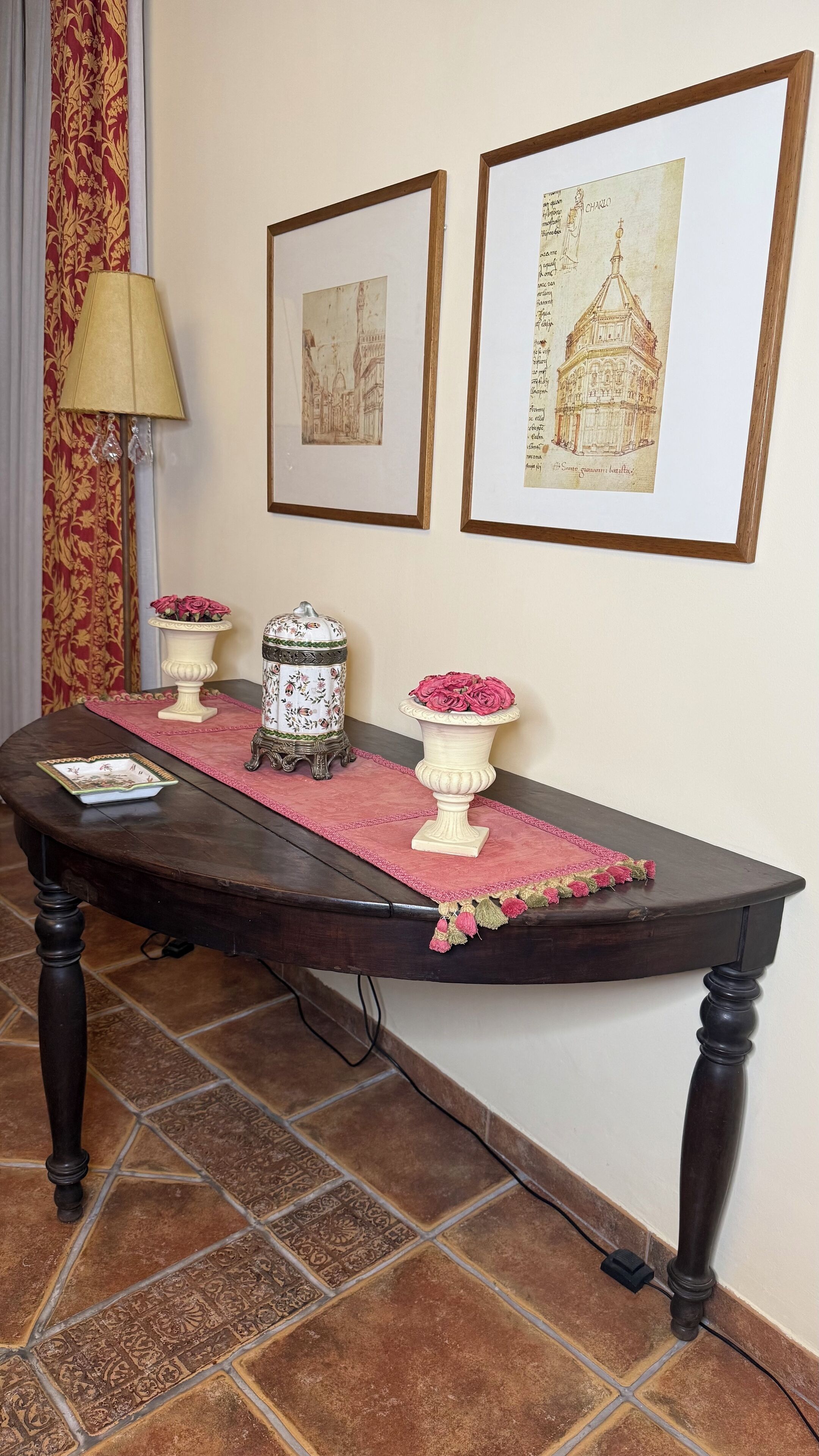 Una mesa de comedor con un jarrón de flores, un plato decorativo y una lámpara.