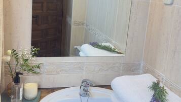 Une salle de bain avec un lavabo blanc, un miroir et un espace douche.