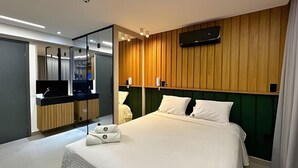 A modern hotel room with a bed, a vanity with a mirror, and a television mounted on the wall. - Get one (Joao Pessoa)