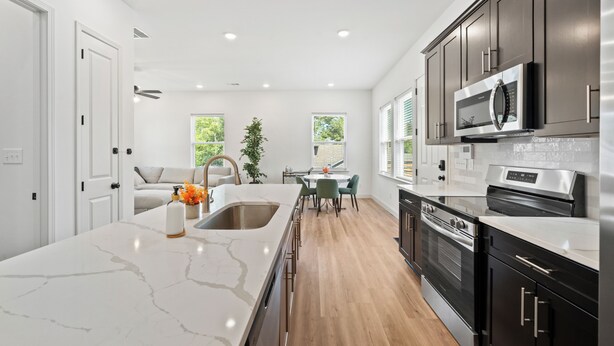 A modern kitchen with a marble island, stainless steel appliances, and a dining area with a view of the outdoors. - Stylish new build 2BR/2BA getaway w/ gated parking (Memphis)