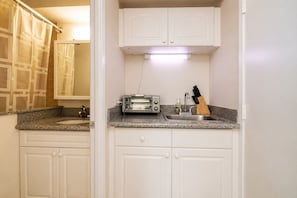 A compact kitchen with white cabinetry, a built-in toaster, a sink, and a knife block.