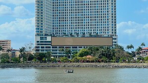 A tall, modern hotel with a grid of windows and a prominent sign at the top. - The Point – Stylish 2-BR w/ Pool, Gym , Private Balcony & Free Parking (Panamá)