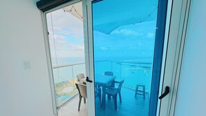 A balcony with a glass door, a table, chairs, and a view of the sea and boats. - The Point – Stylish 2-BR w/ Pool, Gym , Private Balcony & Free Parking (Panamá)