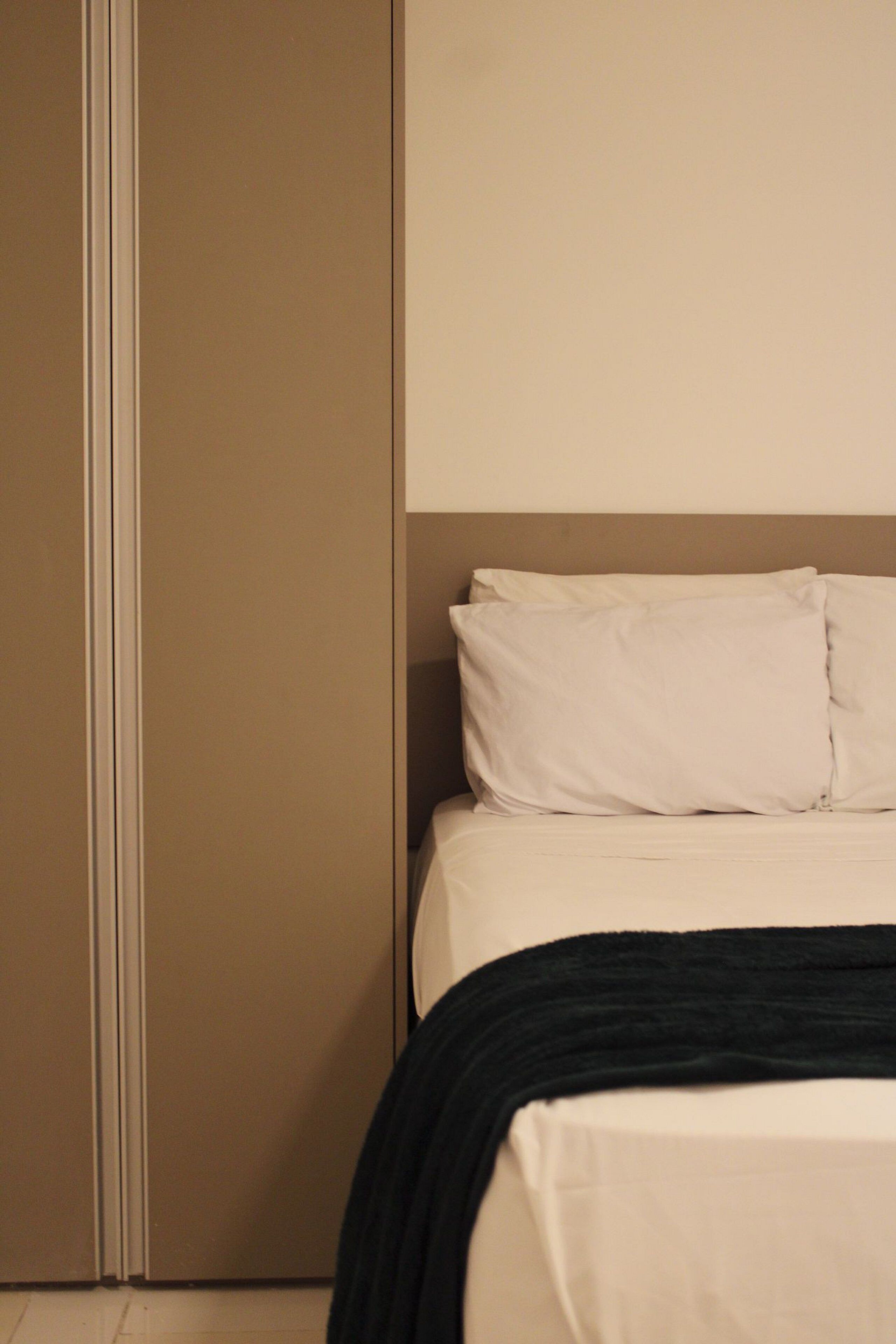 A bedroom with a bed, pillows, and a black throw blanket.