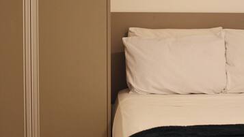 A bedroom with a bed, pillows, and a black throw blanket.