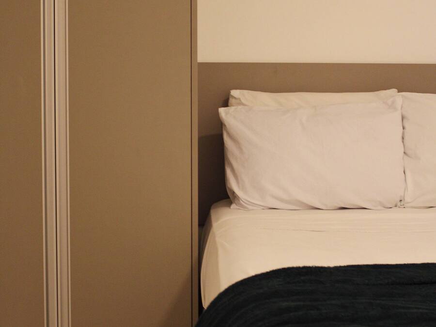 A bedroom with a bed, pillows, and a black throw blanket.