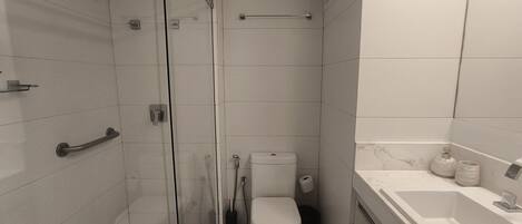 A compact bathroom with a glass shower enclosure, a toilet, and a bathtub.