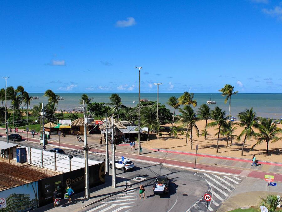 Una intersección frente a la playa con palmeras, una carretera y vistas al océano.
