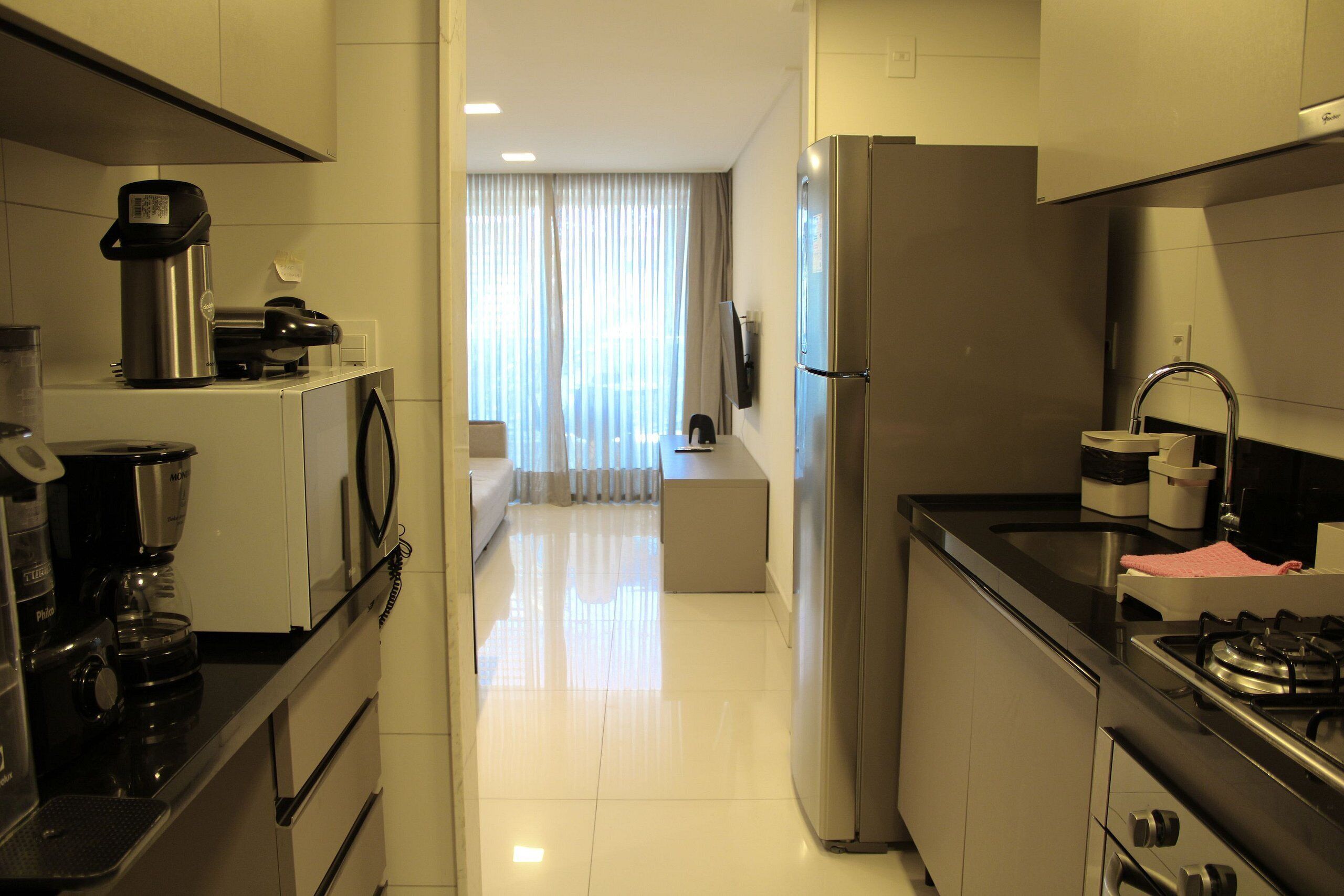 Una cocina moderna con cafetera, refrigerador y estufa.