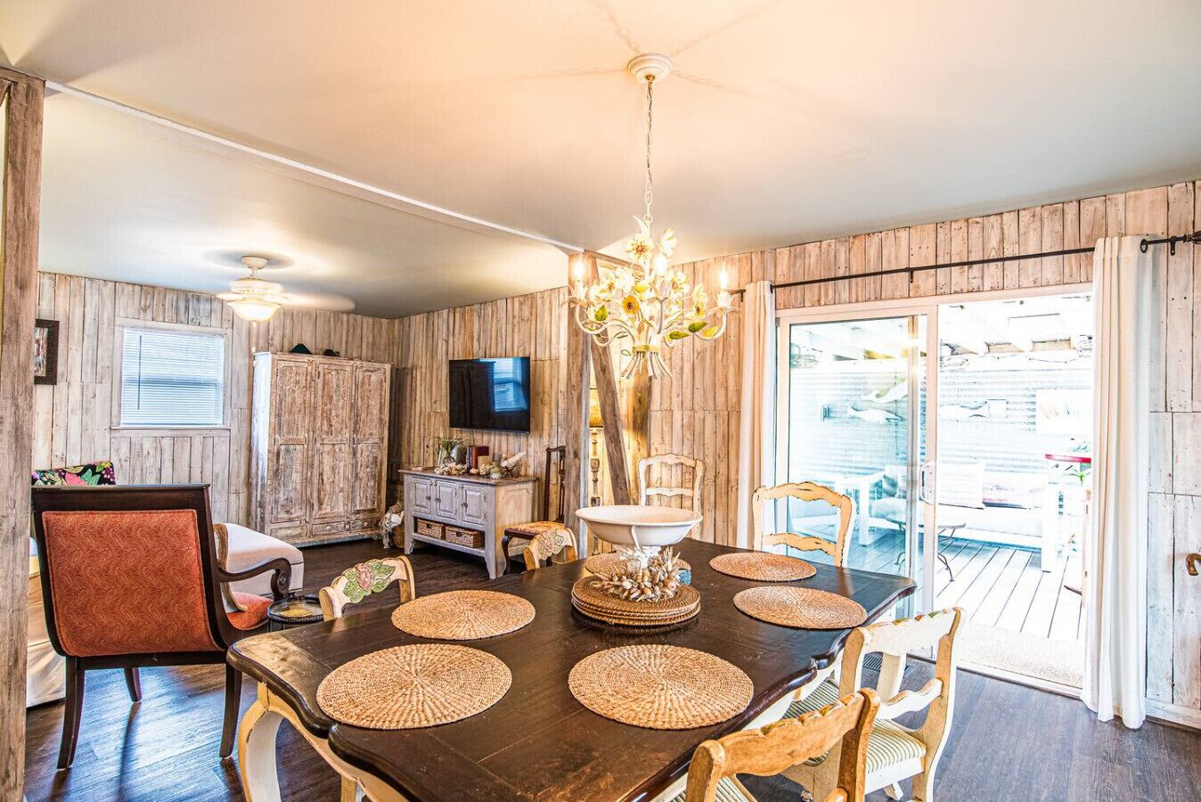 A dining area with a dark wooden table, woven placemats, and a chandelier.