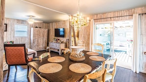 Un coin repas avec une table en bois foncé, des sets de table en fibres tressées et un lustre.