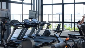 A gym with treadmills, weight machines, and a large window with a view of buildings. - Flat Tambaú aproveite com sua família  (Joao Pessoa)