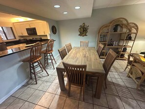 A kitchen with white cabinets, a wooden dining table, and chairs.