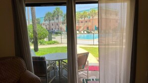 A room with a sliding glass door leading to a balcony with a pool and outdoor furniture.