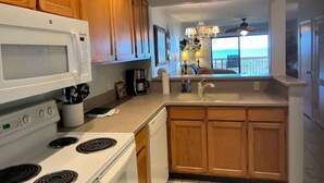 A kitchen with wooden cabinets, a white microwave, stove, and sink.