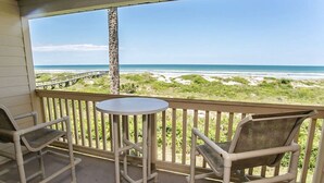 A balcony with a view of the beach and ocean.