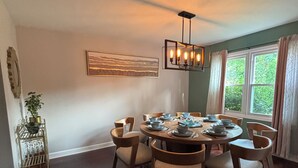 A dining room with a round table set for six, surrounded by wooden chairs. - Galactic Oasis Wonderful 5 bedroom theme home, Wi-Fi, king beds and smart tvs (Aurora)