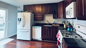 A kitchen with wooden cabinets, a refrigerator, a dishwasher, a stove, and a microwave. - Galactic Oasis Wonderful 5 bedroom theme home, Wi-Fi, king beds and smart tvs (Aurora)