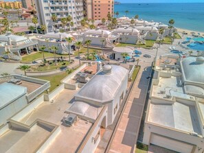 A resort with multiple buildings, a pool area, and a beach view.