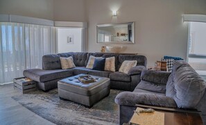 A modern living room with a sectional sofa, ottoman, and a large mirror.