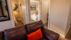 A modern hotel room with a large bed, a seating area with a leather couch, and a painting on the wall. - Cozy Nook Twizel – A Charming Hideaway for Two or a Few (Twizel)