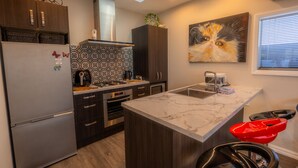 A modern kitchen with a central island, dark wood cabinets, a stainless steel refrigerator, and a skylight. - Cozy Nook Twizel – A Charming Hideaway for Two or a Few (Twizel)