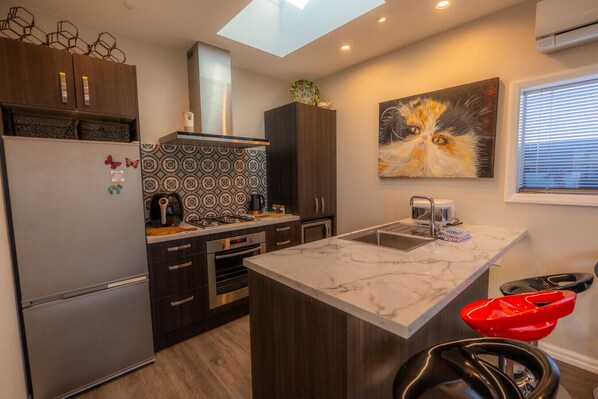Una cocina moderna con una isla central, armarios de madera oscura, un refrigerador de acero inoxidable y un tragaluz.