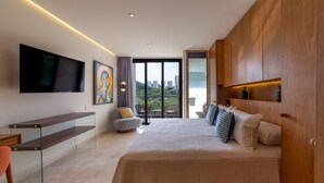 A modern bedroom with a large bed, a TV mounted on the wall, and a balcony with a city view. - Zantamar 502 C (La Cruz de Huanacaxtle)