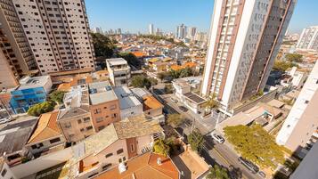 Ein hoch aufragendes Gebäude mit modernem Design, umgeben von einer dicht bebauten Stadtlandschaft mit verschiedenen anderen Gebäuden und wolkenlosem Himmel.