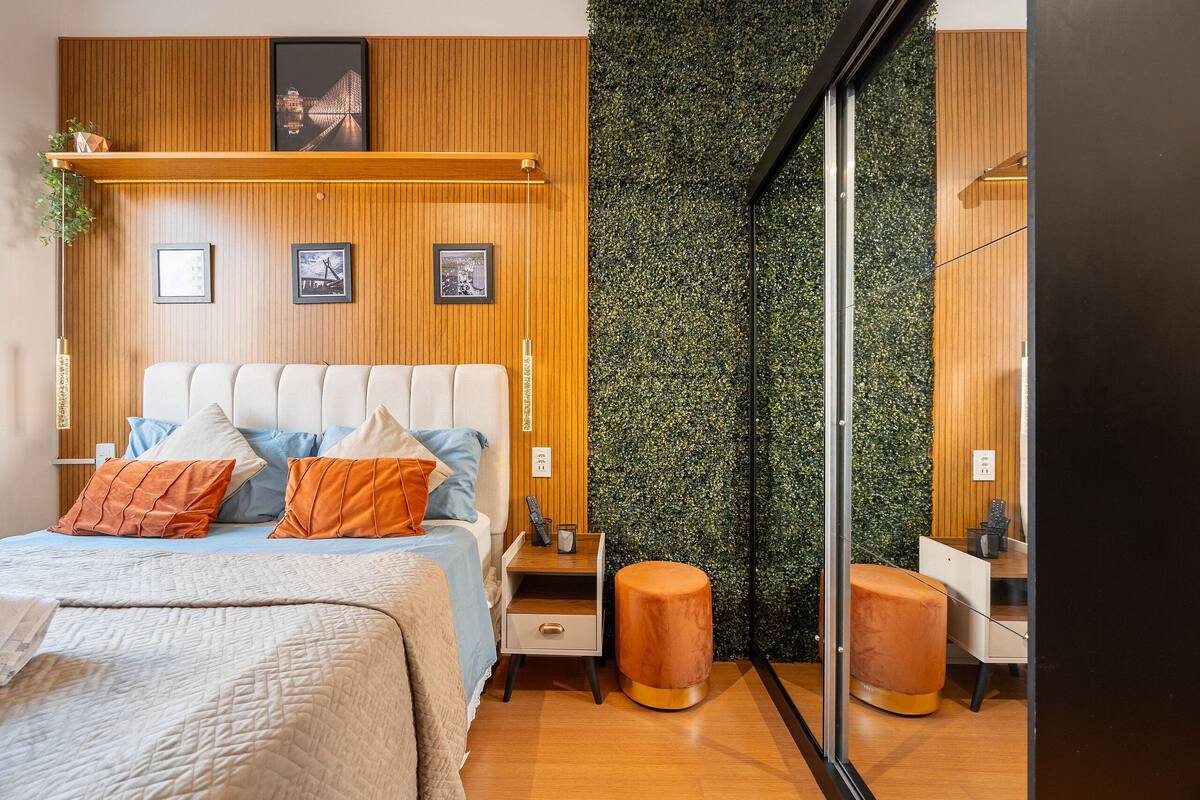 A modern bedroom with a bed, bedside tables, a mirror, and a green wall.
