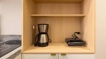 Una cocina con encimera de madera, cafetera y electrodoméstico pequeño.