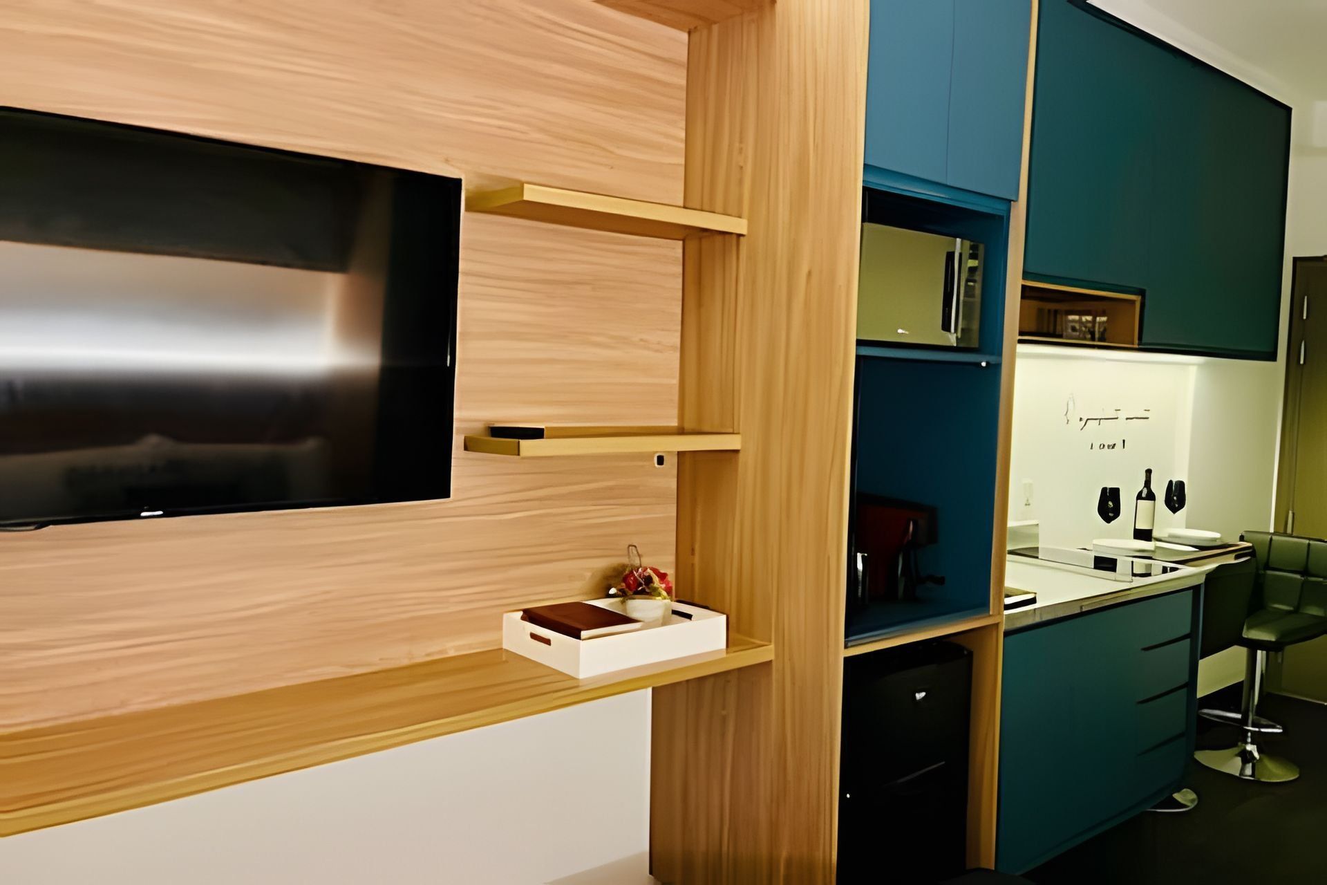 Una cocina moderna con armarios de madera, un televisor integrado y un expositor para vinos.