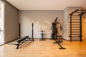 Un gimnasio con una banca, un soporte para pesas y una barra de dominadas.