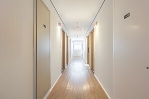 A long, narrow hotel corridor with wooden flooring and white walls. - Estudios Neo Home São Caetano (Sao Caetano do Sul)