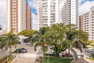Un edificio residencial alto con varios balcones, un estacionamiento con coches y zonas verdes circundantes.