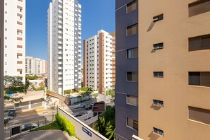 Un immeuble résidentiel de grande hauteur, composé de plusieurs étages, avec un espace de stationnement en premier plan et des bâtiments adjacents présentant différents styles architecturaux.