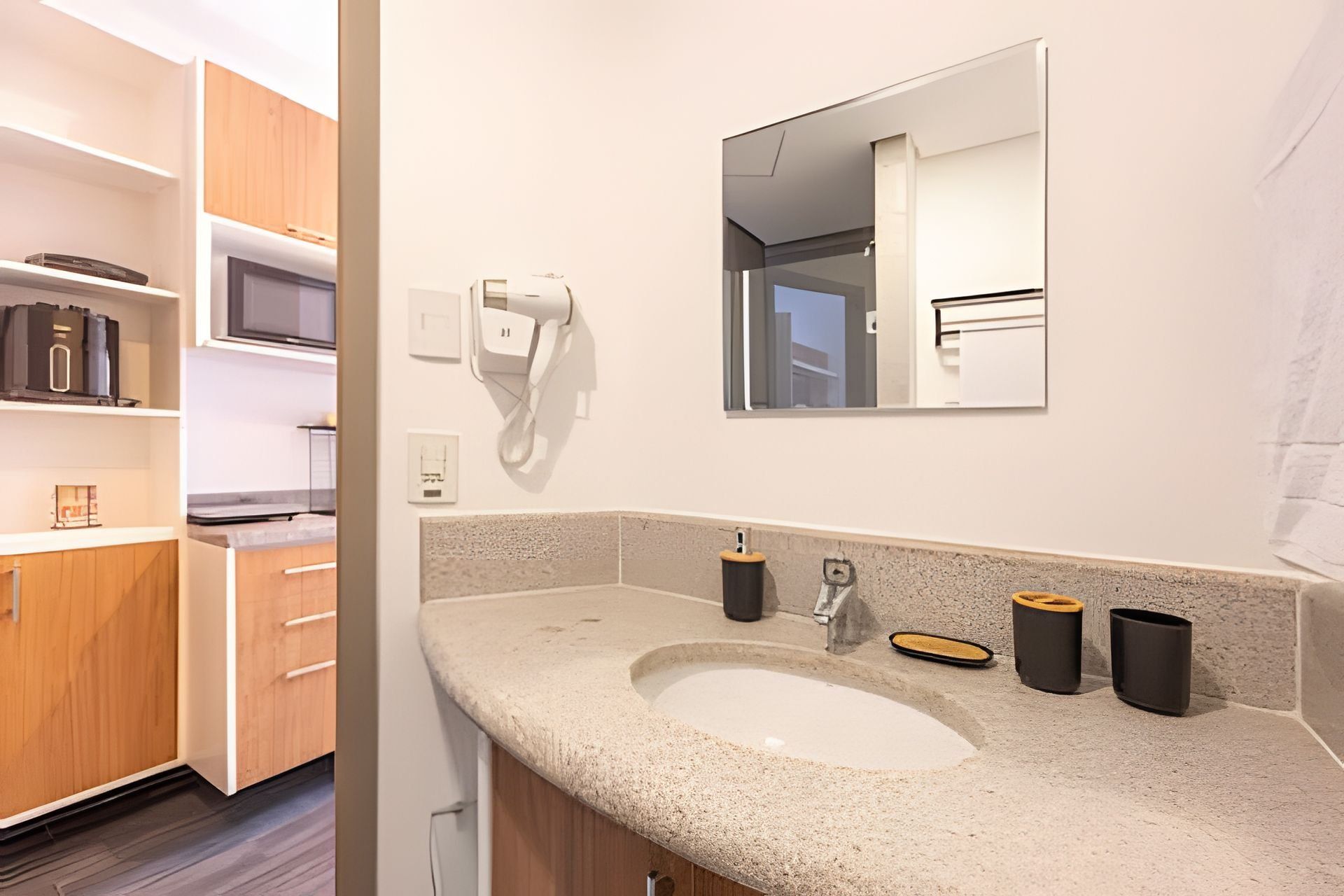 Un bagno moderno con un piano in granito, un lavandino, uno specchio e un porta asciugamani.