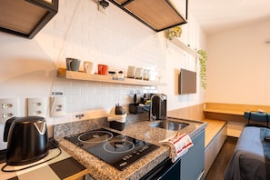 Une petite cuisine équipée avec une plaque de cuisson intégrée, une machine à café et une bouilloire.