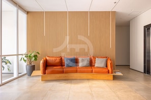 A modern interior with a curved orange leather sofa, a wooden slatted wall, and a potted plant. - Estudios Neo Home São Caetano (Sao Caetano do Sul)