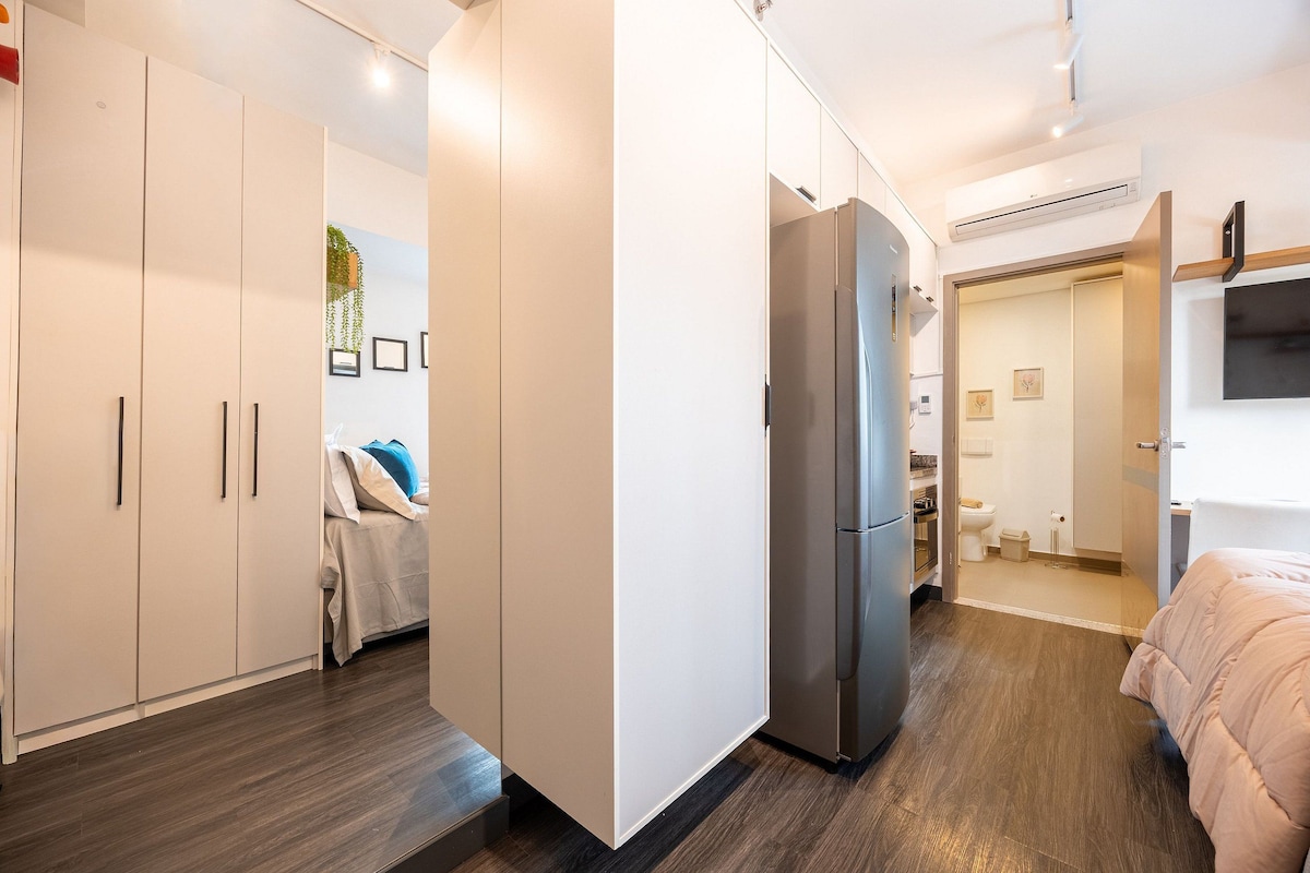 Un dormitorio moderno con cama, armario y refrigerador empotrado.