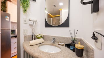 Een moderne badkamer met een granieten blad, een wastafel, een spiegel, een handdoek, een plant en een klein kastje.