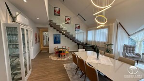 A modern interior with a staircase, dining area, and a seating area with a view. - Apt Luxo 5 suítes em frente rua torta (Gramado)
