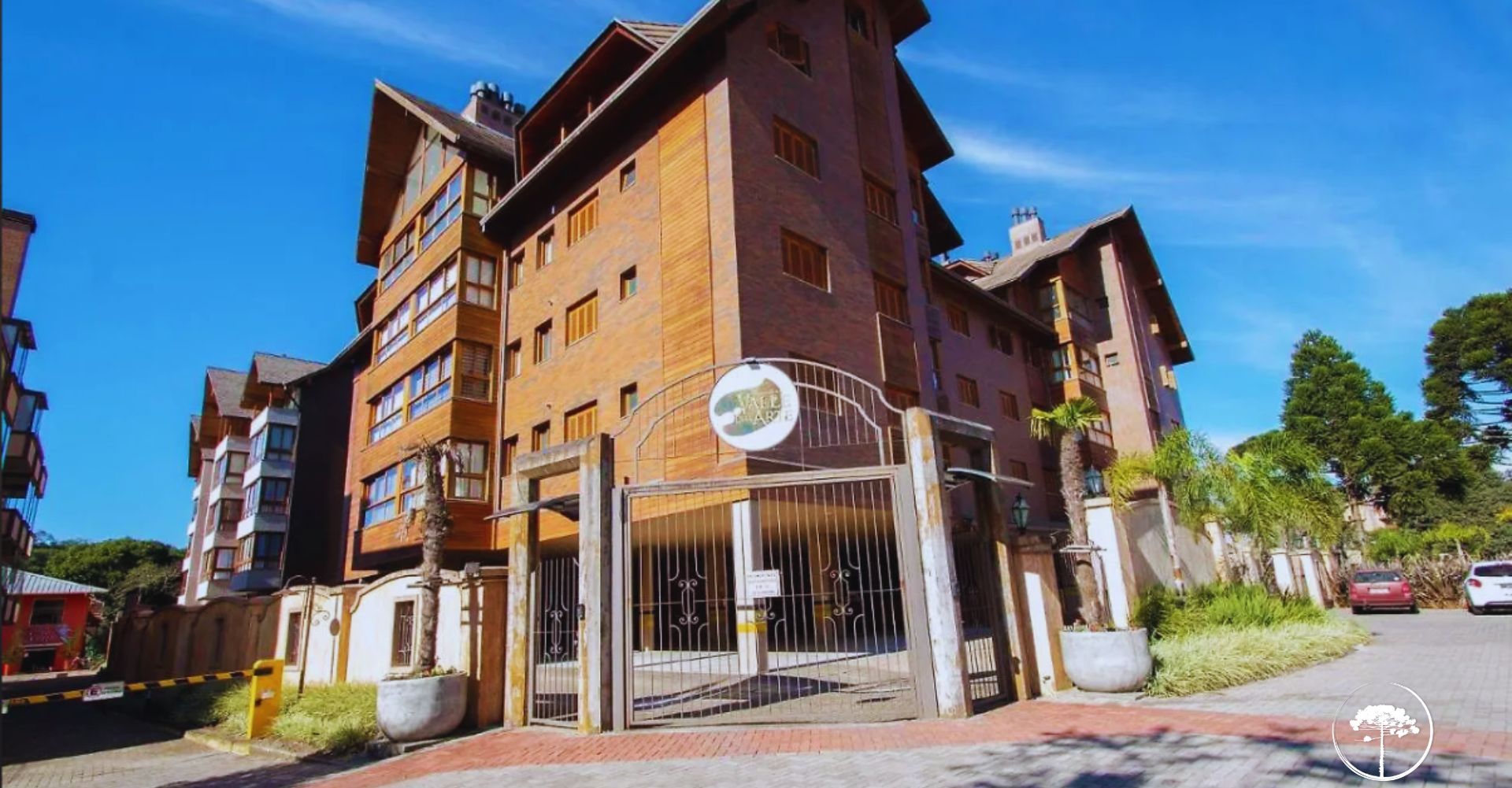 A multi-story residential building with a gated entrance, large windows, and a visible sign indicating a location by temporary arrangement.