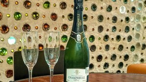A bottle of champagne, two glasses, and a charcuterie board with various meats and cheeses. - Bottle House (San Felipe)