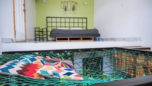 A room with a bed, a hammock, and a hanging plant. - Bottle House (San Felipe)