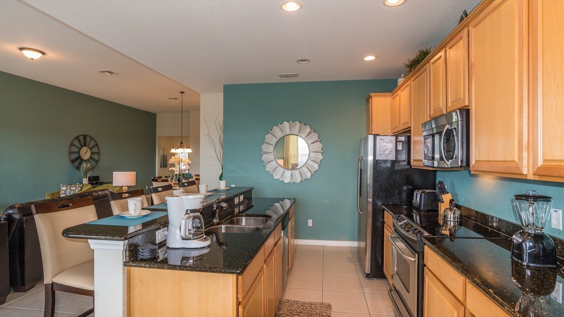 A modern kitchen with wooden cabinets, a stainless steel refrigerator, a microwave, and a coffee maker.