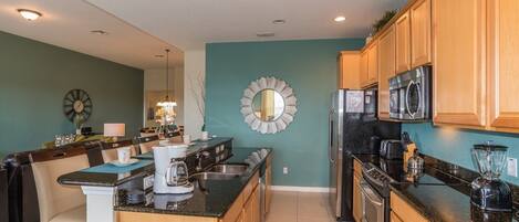 A modern kitchen with wooden cabinets, a stainless steel refrigerator, a microwave, and a coffee maker.