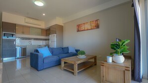 Ein modernes Wohnzimmer mit einem blauen Sofa, einem Holztisch und einer Topfpflanze.