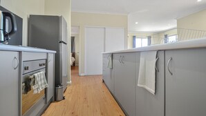 A modern kitchen with grey cabinets, a stainless steel refrigerator, and a wooden floor. - Marvellous McKay 3x2 Close to CBD (Port Hedland)
